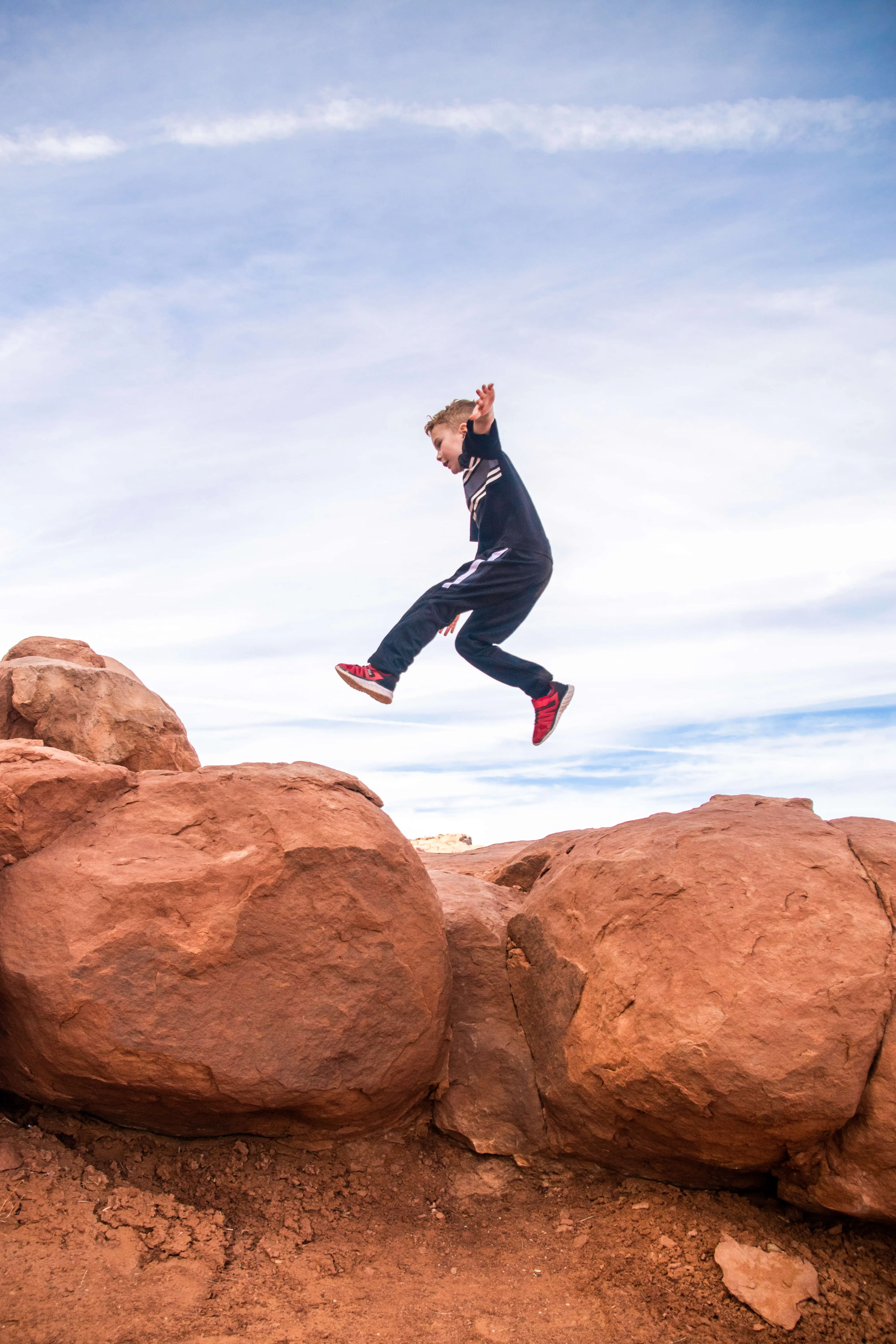 boy jumping on red rocks