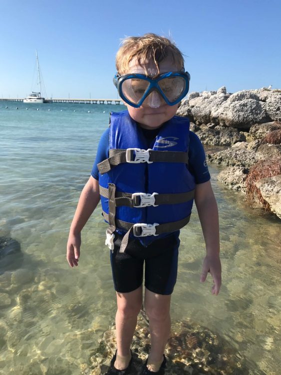 little boy snorkeling with life jacket and wetsuit